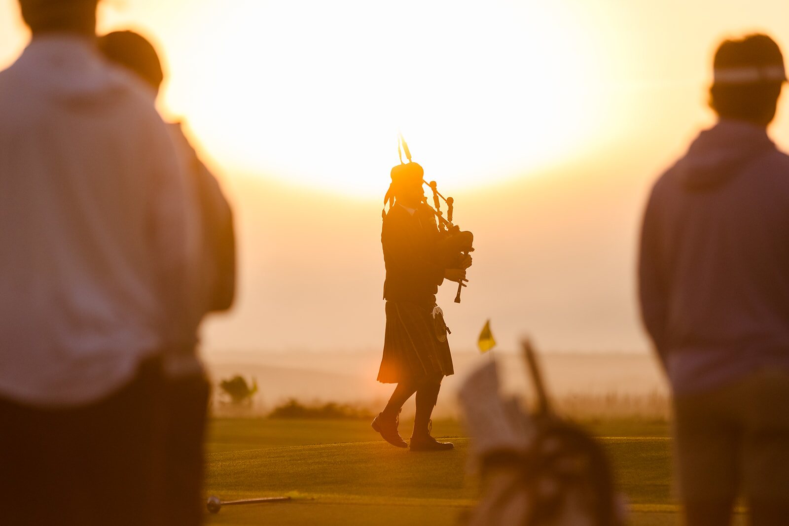 Bagpiper walking into sunrise light at The Ford Collegiate