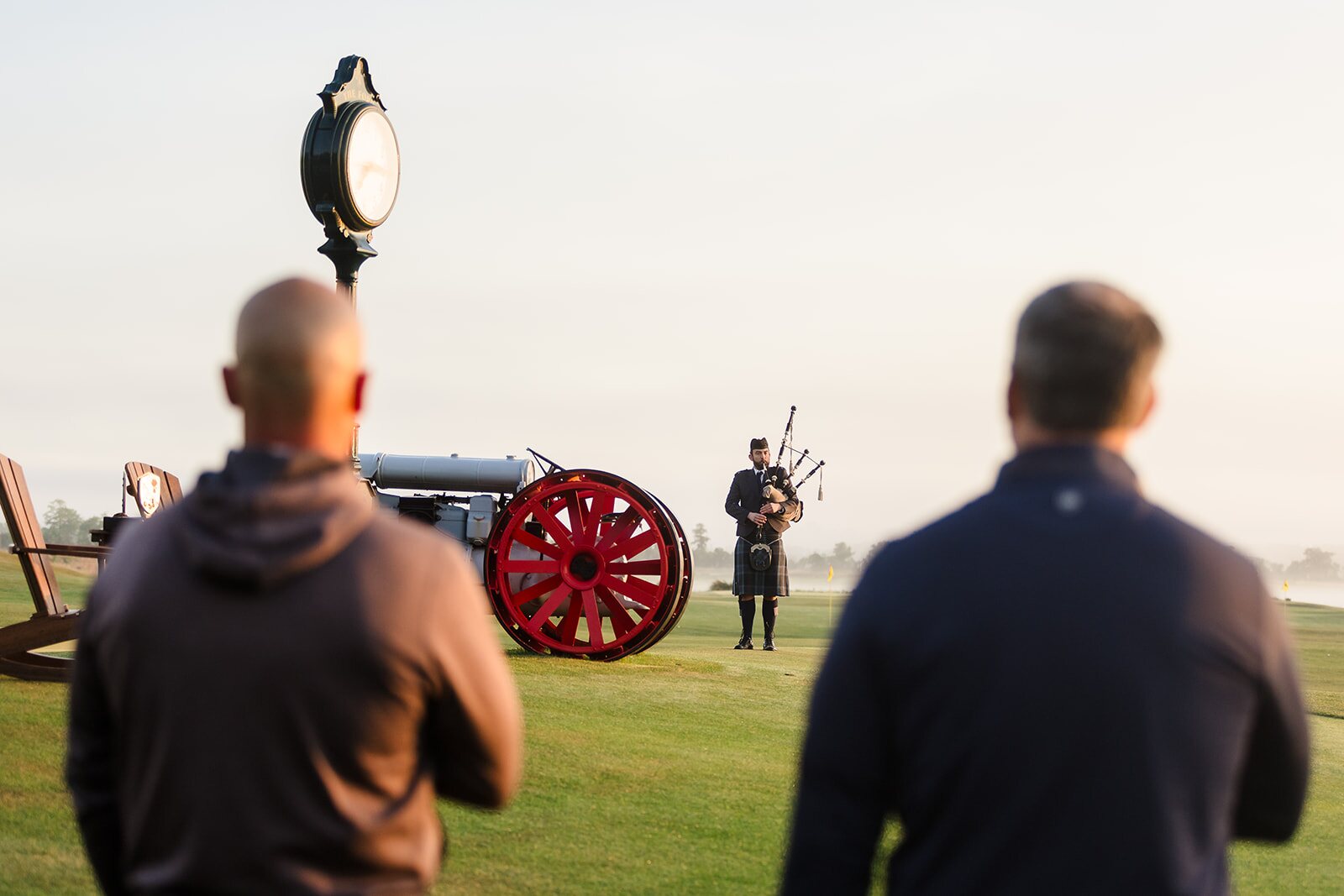 Bagpiper standing near the vintage Ford tractor and course clock